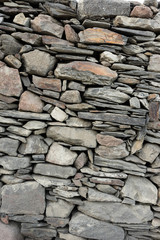 Wall made of natural stone. The texture of the stones of different sizes and shapes that lie on top of each other.