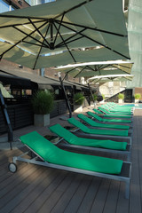 Furniture on the beach. Green sunbeds and parasol at the pool