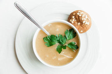 Puree soup with herbs and bread.White plate on the white minimalistic background.Top view.Close-up view