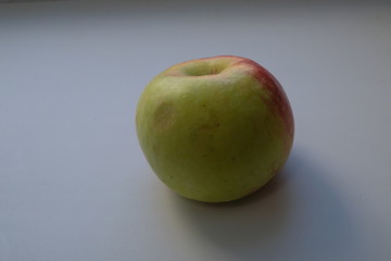 a beautiful apple on a light background, dents are visible on the fruit during transportation