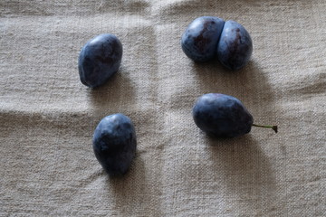 plums of different sizes on a light background of burlap healthy food vitamins