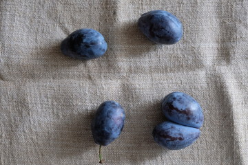 plums of different sizes on a light background of burlap healthy food vitamins