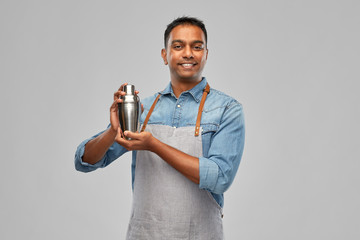 alcohol drinks, people and profession concept - indian barman in apron with cocktail shaker over...