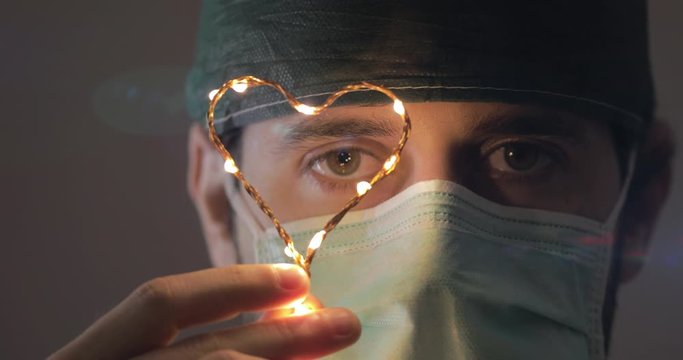 Sguardo di un medico anestesista dopo il turno straziante a curare i pazienti di covid-19. Tiene un cuore come simbolo del ricordo.