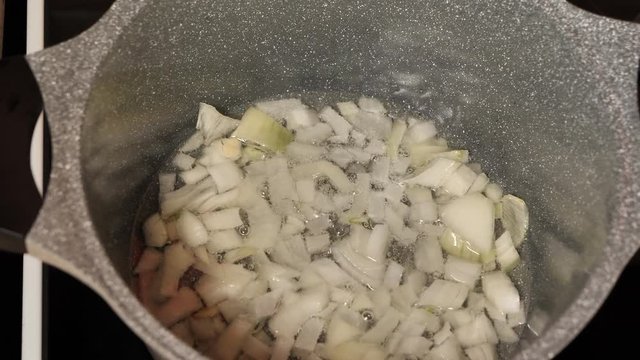 to cook girl fries onions in a pan in olive oil slow motion
