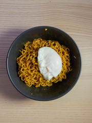 A bowl of fried noodle with egg on top.