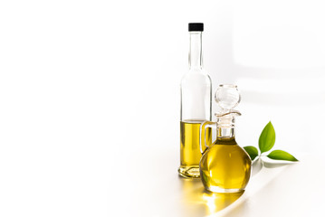 against the window, olive oil in a decanter and in a glass bottle, with a green leaf