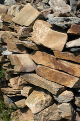 Stone natural flagstone piled in a pile. Natural stone flagstone, laid in uneven rows. Background of the flagstone