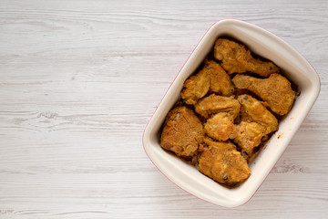 Crispy homemade oven baked fried chicken in a dish on a white wooden surface, top view. Flat lay, overhead, from above. Space for text.