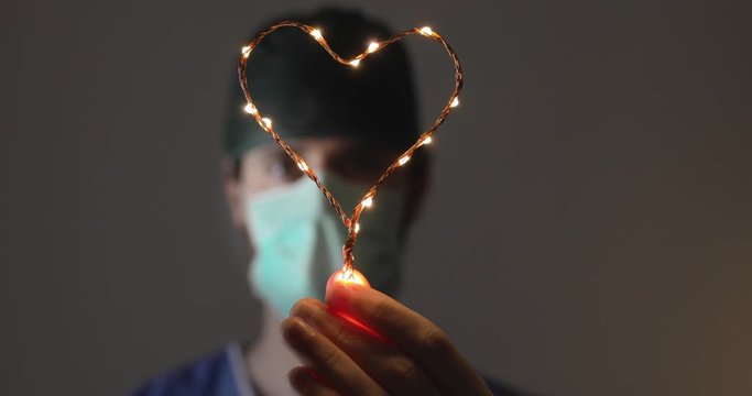 Medico stanco dopo un turno in ospedale mostra un cuore in segno di forza e speranza alla popolazione mondiale. Lotta al Coronavirus.