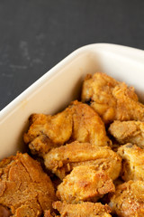 Delicious homemade oven baked fried chicken in a dish on a black surface, low angle view. Copy space.