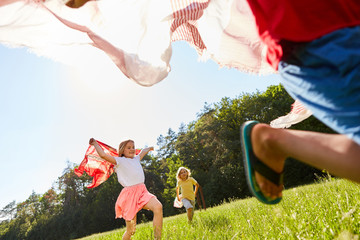 Kinder spielen und laufen mit Tüchern