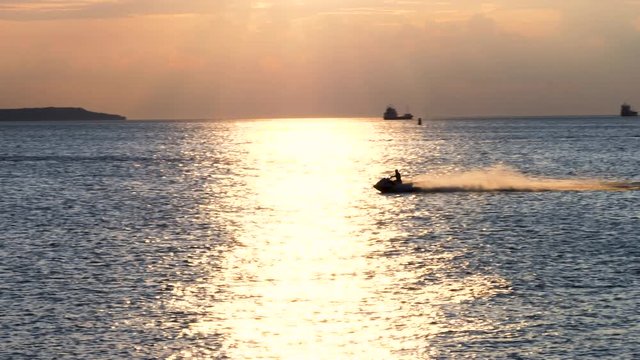 Driving water scooter in sunset on the sea