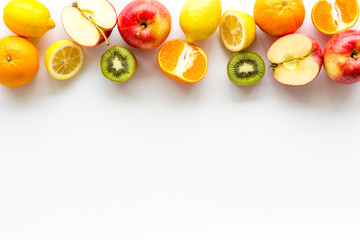 Oranges, lemon, apple, kiwi and grape - healthy food concept with fruits - on white background top-down frame copy space