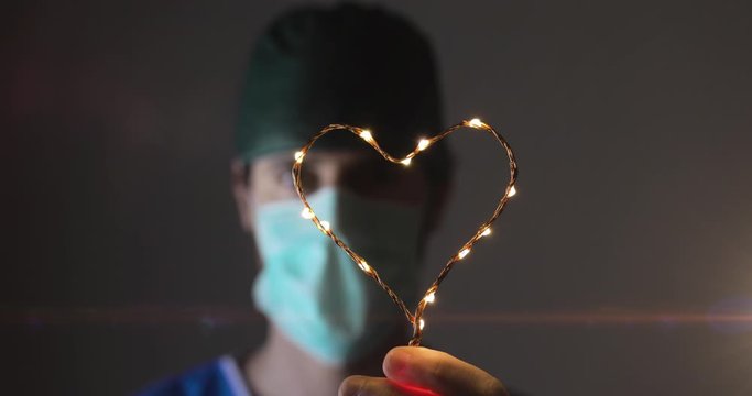 Ospedale in Spagna dopo i contagi da Coronavirus. Giovane medico tiene in mano un cuore per dare speranza alla popolazione. Lotta contro il virus.