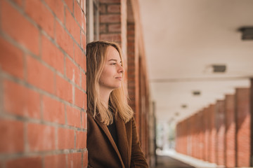 Cute fashionable young woman in a red brick hallway looking away in the distance. Caucasian girl in...