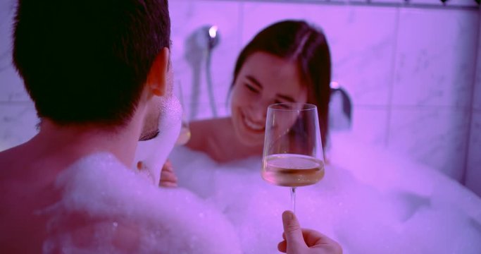 newly married couple are enjoying bubble bath and champagne in first wedding night