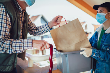 Teenage girl is delivering some groceries to an elderly person.Contactless delivery during the...