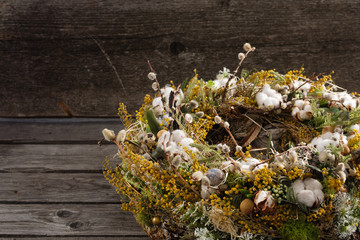 Wreath of dried twigs and flowers on a wooden background. Natural decoration. Celebration concept. Easter wreath. Willow round frame. Close-up.