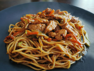 Pork chow mein on a black plate. Selective focus.