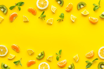 Slices fruites frame. Fruit salad concept with citruses, aplle and kiwi on yellow background top-down copy space