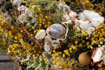 Wreath of dried twigs and flowers on a wooden background. Natural decoration. Celebration concept. Easter wreath. Willow round frame. Close-up.