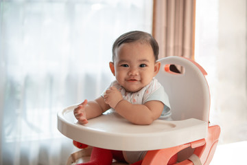 happy asian baby feeding time sitting on highchair