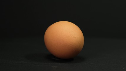 Brown egg rotating on black background. Close up.
