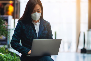 Closeup image of a sick woman wearing protective face mask, using laptop computer for Healthcare and Covid-19 concept