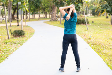 Portrait long hair Asian runner woman stretching arm and hand before run in the garden.Young fitness woman exercise in the public park.