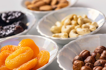 Dried fruits apricots and prunes, various nuts and almond kernels in plates close up