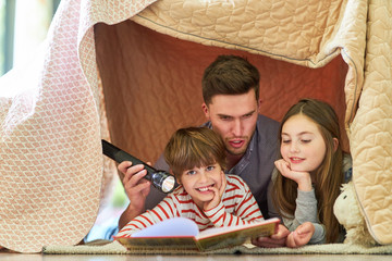 Father is reading an exciting story to children