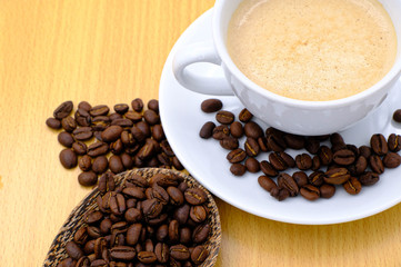 Coffee cup and beans on wooden kitchen table. Top view with morning sunlight