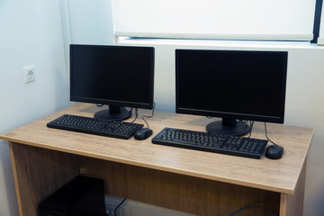 two computers and a desk . Keyboard and mouse . Two computer monitors with a black screen on a desk .
