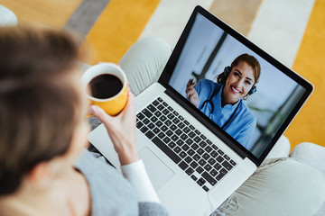 Young happy doctor having video call with patient who is calling her from home.
