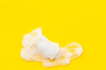 Soap bar with foam on yellow background top-down copy space