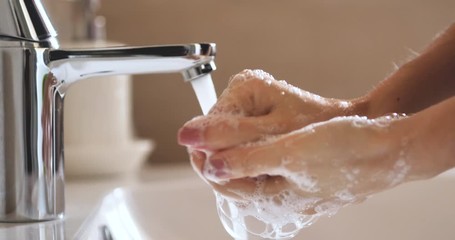 Close up shot of an young woman applying soap while washing hands for hygiene purpose in washbowl with open tap. Concept of personal hygiene, cleanliness, sanitary, disinfection - Powered by Adobe