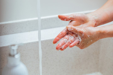 Fototapeta premium Close-up of woman cleaning hands with soap in the bathroom.