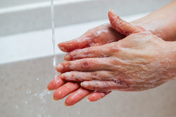Fototapeta premium Close-up of woman rubbing hands with a soap in the bathroom.
