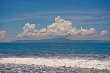 Beautiful landscape on waves of clouds and an island in the ocean.