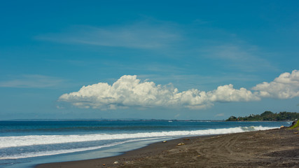Beautiful landscape on waves of clouds and an island in the ocean. Keramas beach, Bali, Indonesia.