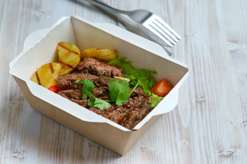 grilled steak and vegetables in a shipping container