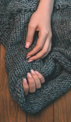 Women's hands on a knitted fabric on a wooden background