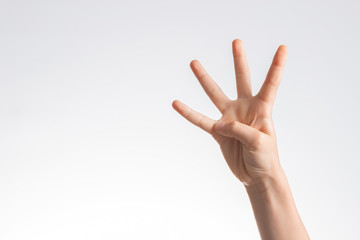 Kid hand showing and pointing up with fingers number four on white wall background