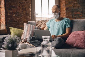 Typing text. Young man doing yoga at home while being quarantine and freelance online working. Remote office, isolated. Concept of healthy lifestyle, wellness, being safe while coronavirus pandemic.