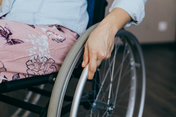 Unrecognizable disabled woman in wheelchair at home. Recovery and healthcare concepts.