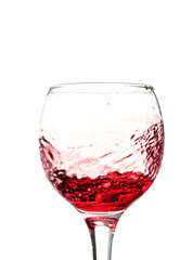 Splash of falling red wine in a round glass on a white background