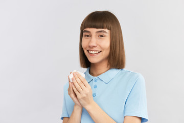 happy young girl holding white tissue after blowing nose and looking to camera with smile