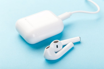 wireless bluetooth headphones with charging case and wire on a blue background.