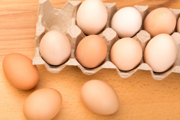 brown chicken eggs in an open cardboard box with eggs on a wooden table. Natural healthy food.